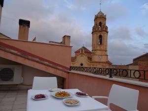 a table and chairs on a balcony with a clock tower at Ca la Victòria in Vinyols i els Arcs