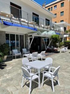 Piccolo hotel le Palme في سان بارتولوميو آل مار: طاولة بيضاء وكراسي أمام المبنى