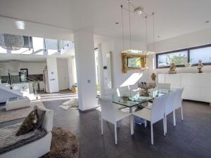 uma sala de jantar com uma mesa de vidro e cadeiras brancas em Architect modern design villa in Sitges Hills em Olivella