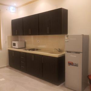 a kitchen with black cabinets and a white refrigerator at روح الأصيلة للشقق المخدومة Roh Alaseilah Serviced Apartments in Taif