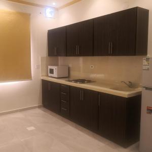 a kitchen with black cabinets and a white microwave at روح الأصيلة للشقق المخدومة Roh Alaseilah Serviced Apartments in Taif
