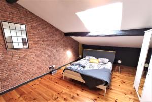 een slaapkamer met een bakstenen muur en een bed bij LA TERRASSE DE JEANNE - Vue Magnifique - Netflix in Toulouse