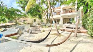 a hammock on the beach in front of a house at Lola by Coco B Isla in Isla Mujeres
