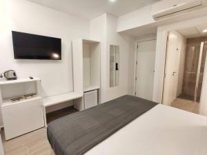 a white bedroom with a bed and a flat screen tv at GLOBAL Apartments & Rooms in Hospitalet de Llobregat