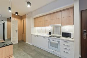 a kitchen with white cabinets and a microwave at D Apartments Centrum Jurowiecka II in Białystok