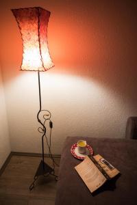 eine Lampe auf einem Tisch mit einer Tasse und einer Zeitung in der Unterkunft Dunavska bajka in Vinci