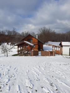 a log cabin in the snow with footprints in the snow at Holiday Apartman Ravna Dolina in Cetingrad