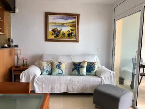 a living room with a couch and a painting on the wall at PINEDA BEACH 1a línea de mar & parking in La Pineda