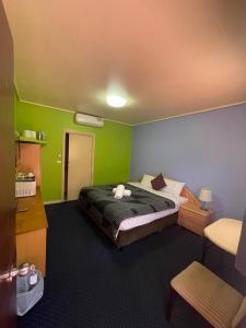 a room with a bed, a desk, and a lamp at City East Motel in Melbourne