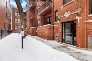 a snow covered sidewalk in front of a brick building at Chic & Updated Studio Apt in East Lakeview - Barry S1 in Chicago