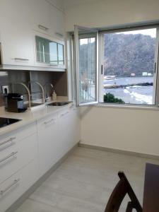 uma cozinha com armários brancos e uma grande janela em Apartamento Area Pequena Ézaro 2 em Ézaro