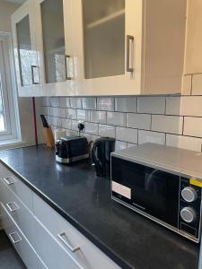 a kitchen with a black counter top with a microwave at Beautiful apartment right off of Broadway Market in London