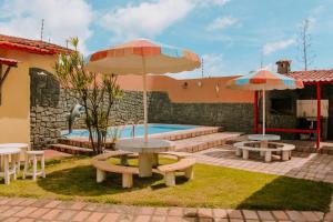 un patio con tavoli e ombrelloni accanto alla piscina di Belíssima casa de temporada próximo ao mar a Natal