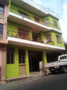 un edificio verde con un camión estacionado frente a él en Hosteria del Centro en Santiago Atitlán