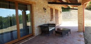 a patio with glass doors and a bench and a table at Meriggio Agriturismo in Fiastra