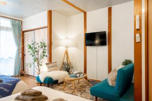 a living room with a blue couch and a tv at Type B Room 27平米 - ウル エスポワール那覇2- in Kume