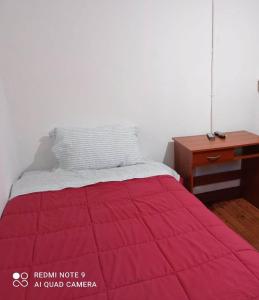 1 cama con manta roja y escritorio en Hospedaje curicó casa grande en Curicó