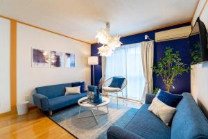 ein Wohnzimmer mit einem blauen Sofa und einem Tisch in der Unterkunft Type B Room 40平米 -ウル エスポワール那覇- in Naha