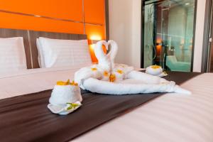 two swans made out of towels on a bed at The Proud Hotel Pattaya - SHA Certified in North Pattaya