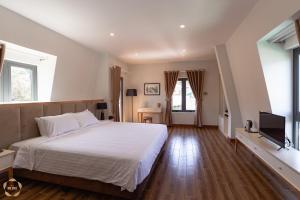a bedroom with a white bed and a television at Hotel Du Ciel in Da Lat