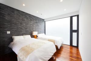 two beds in a bedroom with a brick wall at E-horizon Resort Premium 瀬底B in Sesoko
