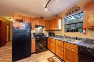a kitchen with wooden cabinets and a black refrigerator at Bearfootin' Holiday home in Sevierville