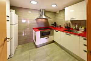 uma cozinha com armários brancos e um balcão vermelho em Unsejouraempuriabrava-TERRASSE-VUE MER -CLIME- WIFI PARKING em Empuriabrava