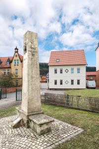 un monument en pierre devant un bâtiment blanc dans l'établissement Am Landhof Ferienwohnung, à Heilbad Heiligenstadt