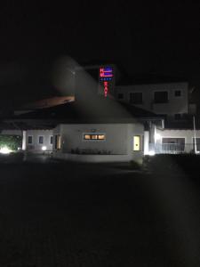uma casa com um sinal de néon no telhado à noite em Elysium Hotel Raya em Mediglia