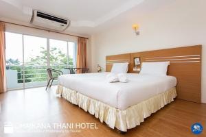 a bedroom with a large white bed and a balcony at Chaikana Thani Hotel in Phatthalung