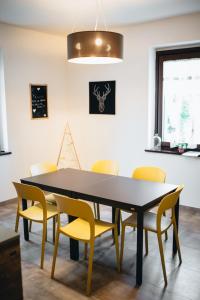 a dining room with a black table and yellow chairs at Agriturismo La Casa Gialla in Romagnano