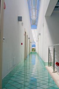 a hallway with a green tile floor and a blue ceiling at Ganimede Hotel in Sperlonga