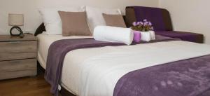 ein Schlafzimmer mit einem Bett mit lila Bettwäsche und Blumen darauf in der Unterkunft Apartman Soko in Sokobanja