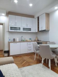 a kitchen with white cabinets and a table and chairs at Central and Quiet in Pančevo