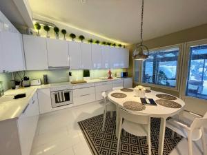 a kitchen with white cabinets and a white table and chairs at Design Guesthouse Laanila in Oulu