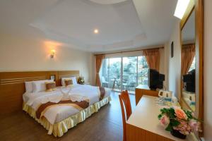Schlafzimmer mit einem Bett, einem Schreibtisch und einem TV in der Unterkunft Chaikana Thani Hotel in Phatthalung