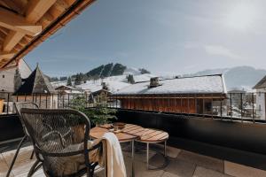 einen Balkon mit einem Tisch und Stühlen sowie einem schneebedeckten Dach in der Unterkunft PoSt Boutique Apartments in Maria Alm am Steinernen Meer