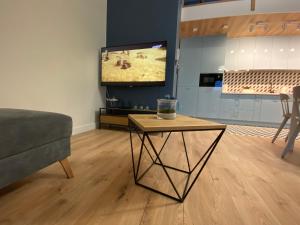a living room with a table and a flat screen tv at APARTAMENT KRYNICA MORSKA in Krynica Morska