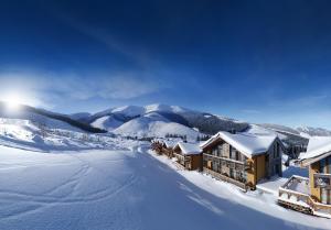 a lodge in the snow with mountains in the background at Chalety Jasná Apartmány Bor in Belá
