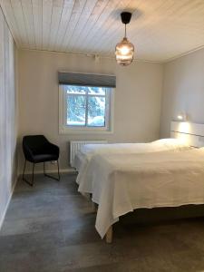 a bedroom with a bed and a chair and a window at Soukolo Apartments in Äkäslompolo