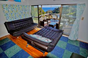 - un salon avec un canapé en cuir et une chaise dans l'établissement Breathtaking View House, à Itō