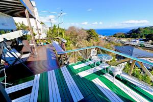 a balcony with a table and chairs and the ocean at Breathtaking View House in Ito