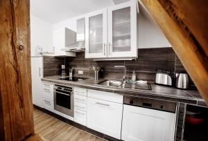 uma cozinha com armários brancos e um lavatório em Ferienwohnung Julia em Suhl