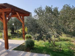 a wooden pavilion in a park with a tree at Olive Apartments in Ugljan