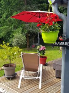 une chaise assise sur une terrasse avec un parasol rouge dans l'établissement Clos des Morillons, à Vénérand