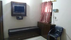 a living room with a tv and a chair at Basil Inn Home Stay Walking Distance From Taj Mahal Agra in Agra +11 photos