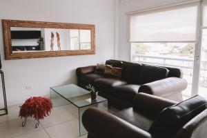 a living room with a leather couch and a mirror at Administración MAIPU 2E DEPTO PREMIUM in Tandil +2 photos