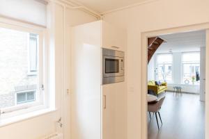 cocina y sala de estar con microondas y ventana en By de Buurvrouw, en Kollum