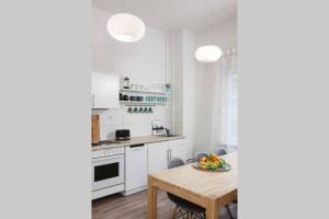 cocina con armarios blancos y mesa de madera en City Apartment near Shooping Center, 6 guests, en Berlín