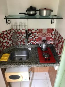 a kitchen counter with a sink and a stove at Amarelo Hibisco in Guarda do Embaú +102 photos